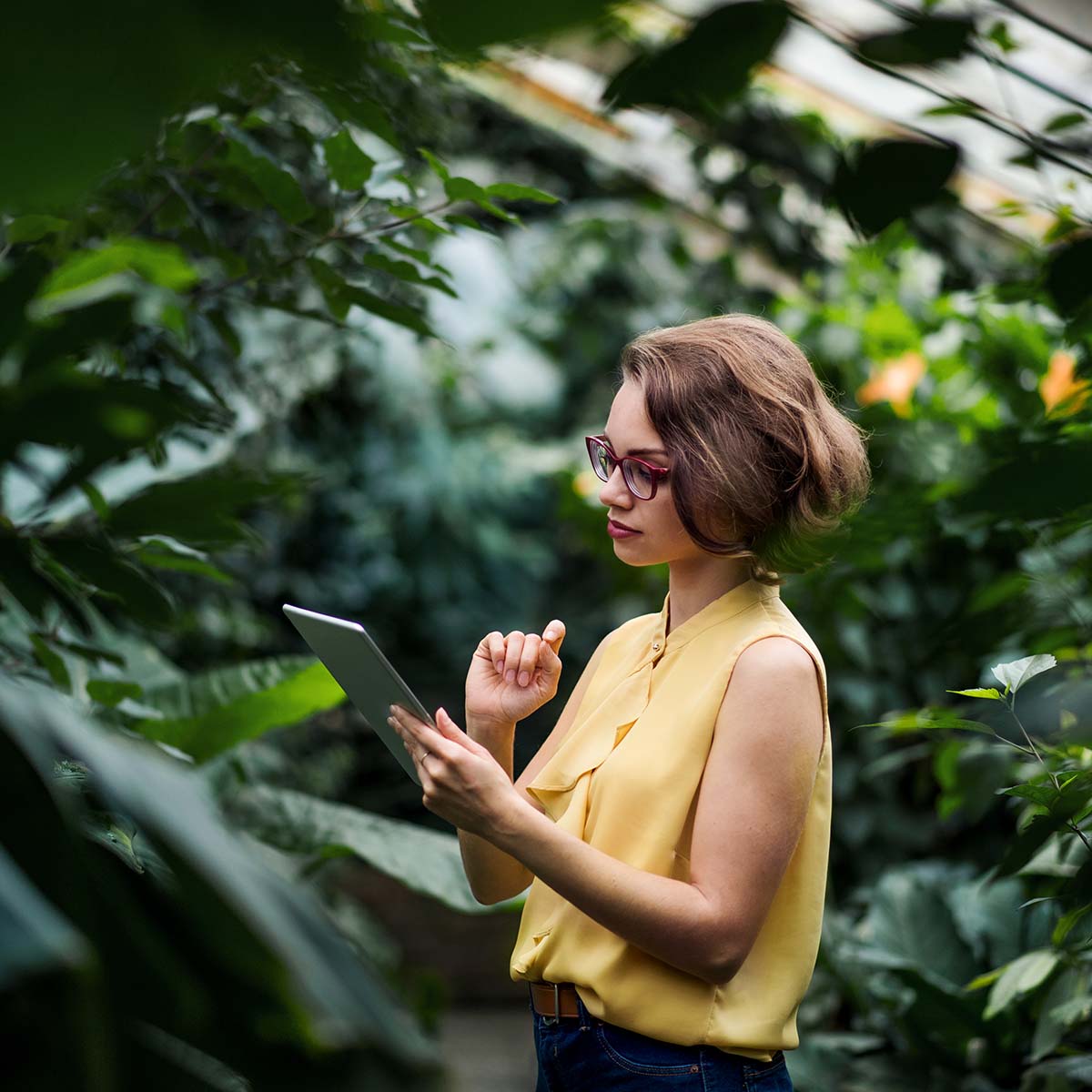 young-woman-standing-in-greenhouse-in-botanical-4KLTJ7M.jpg